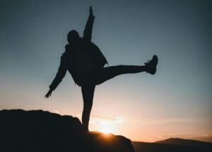 Silhouette of a person balancing on a rock during sunset in Ortahisar, Nevşehir, Türkiye.