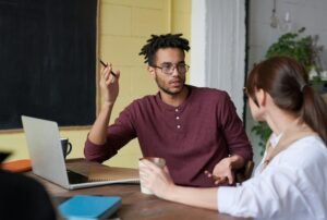 Two colleagues engaged in a collaborative discussion during a team meeting at the office.